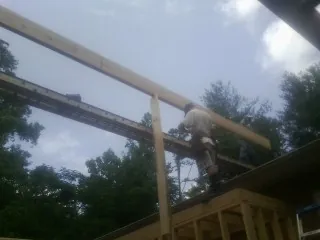 Carpenter setting a ridge beam over a new addition frame — Ice Dam Removal by Roofing Brothers in Heath Springs
