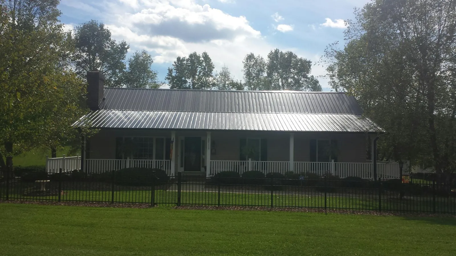 Gray metal roof on a brick ranch with a full width front porch — Gutter Guard Installation work by our crew in Heath Springs