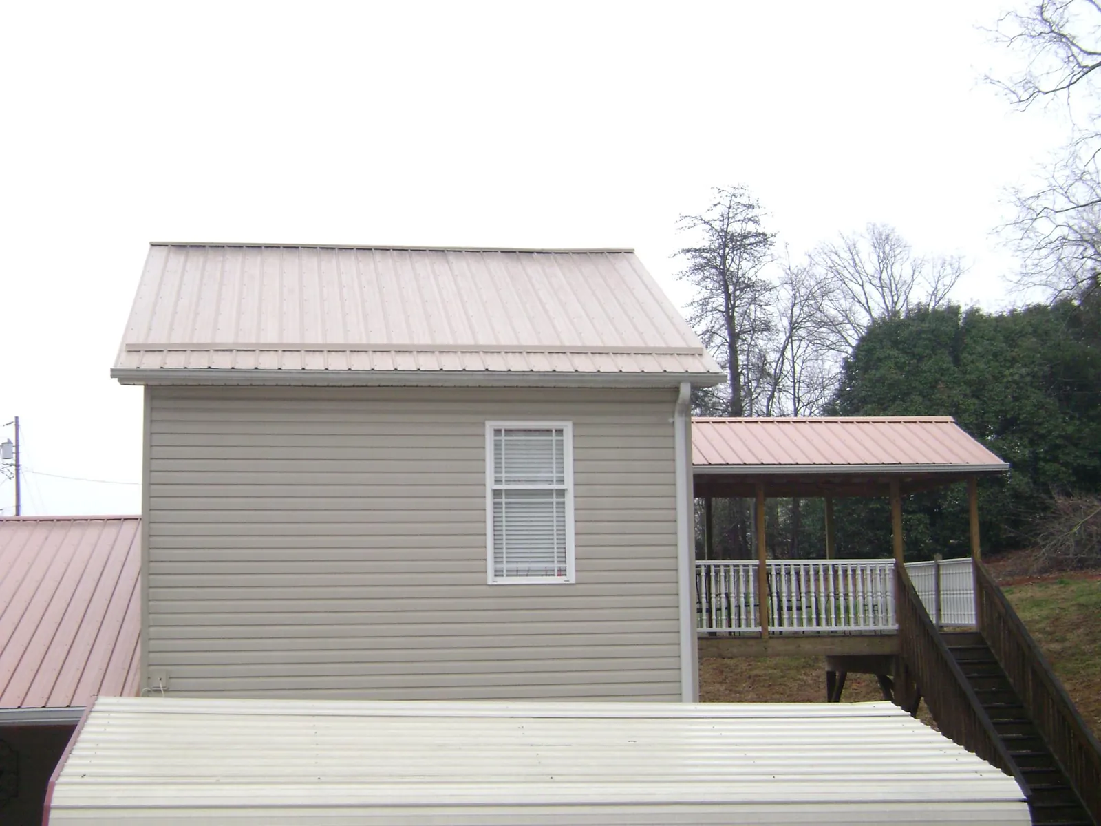Tan metal roofs on a two story addition and attached porch, from a Roof Replacement job in Heath Springs