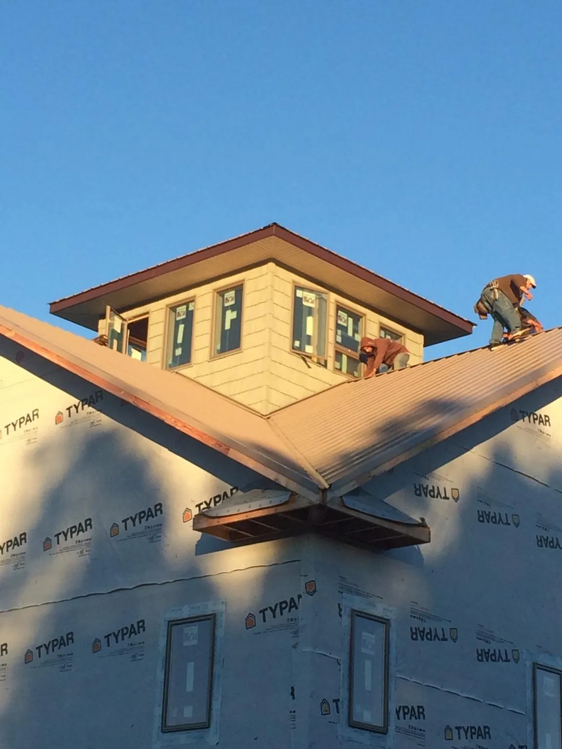 Roofers working around a rooftop cupola on a new metal roof at sunset — Roof Waterproofing in Heath Springs by Roofing Brothers